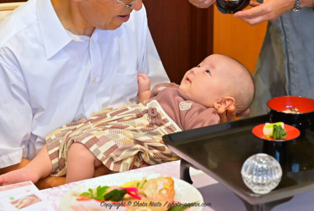 お食い初め、祖父様に微笑む赤ちゃん