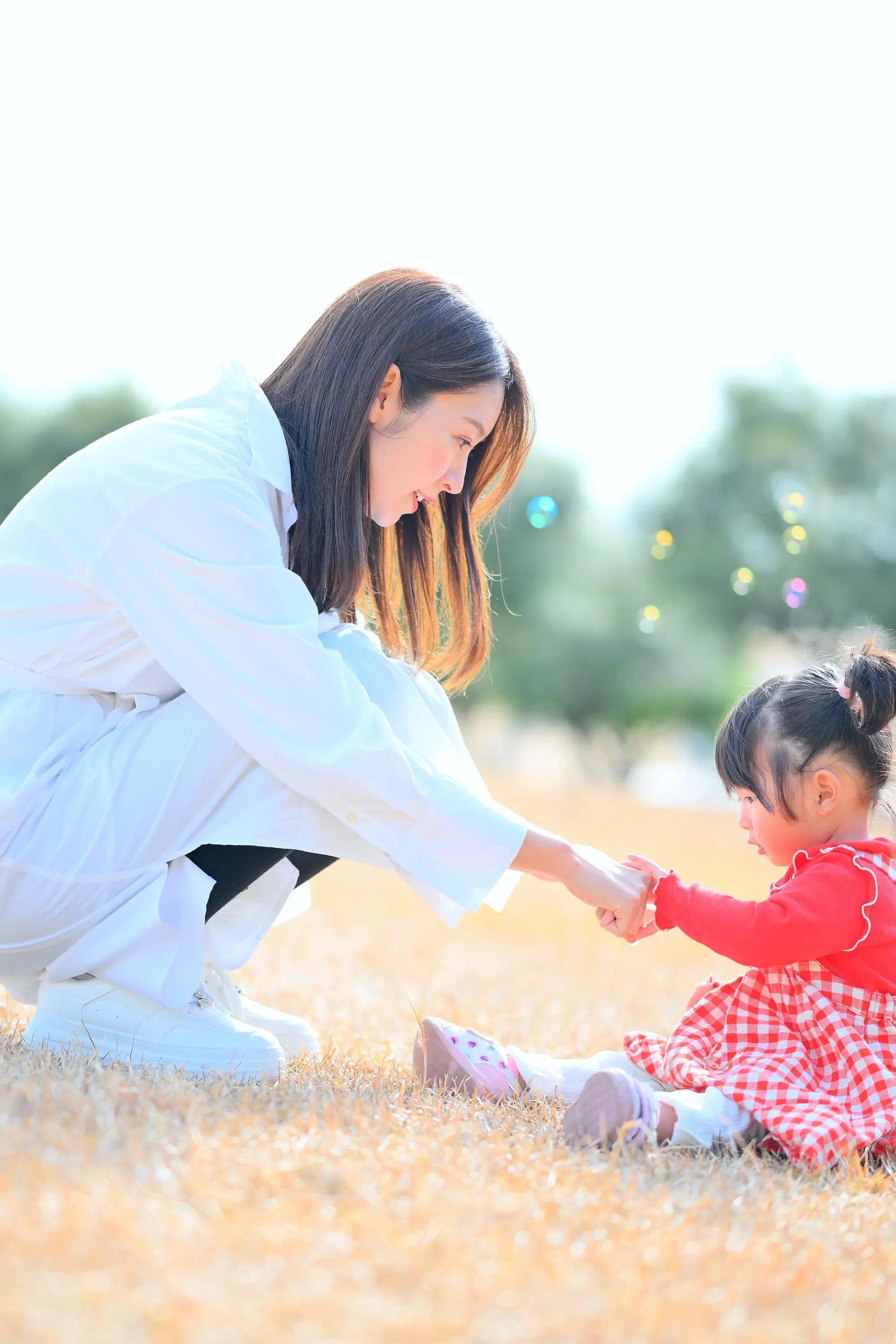公園での芝生の上で手遊びするママと娘のポートレート写真