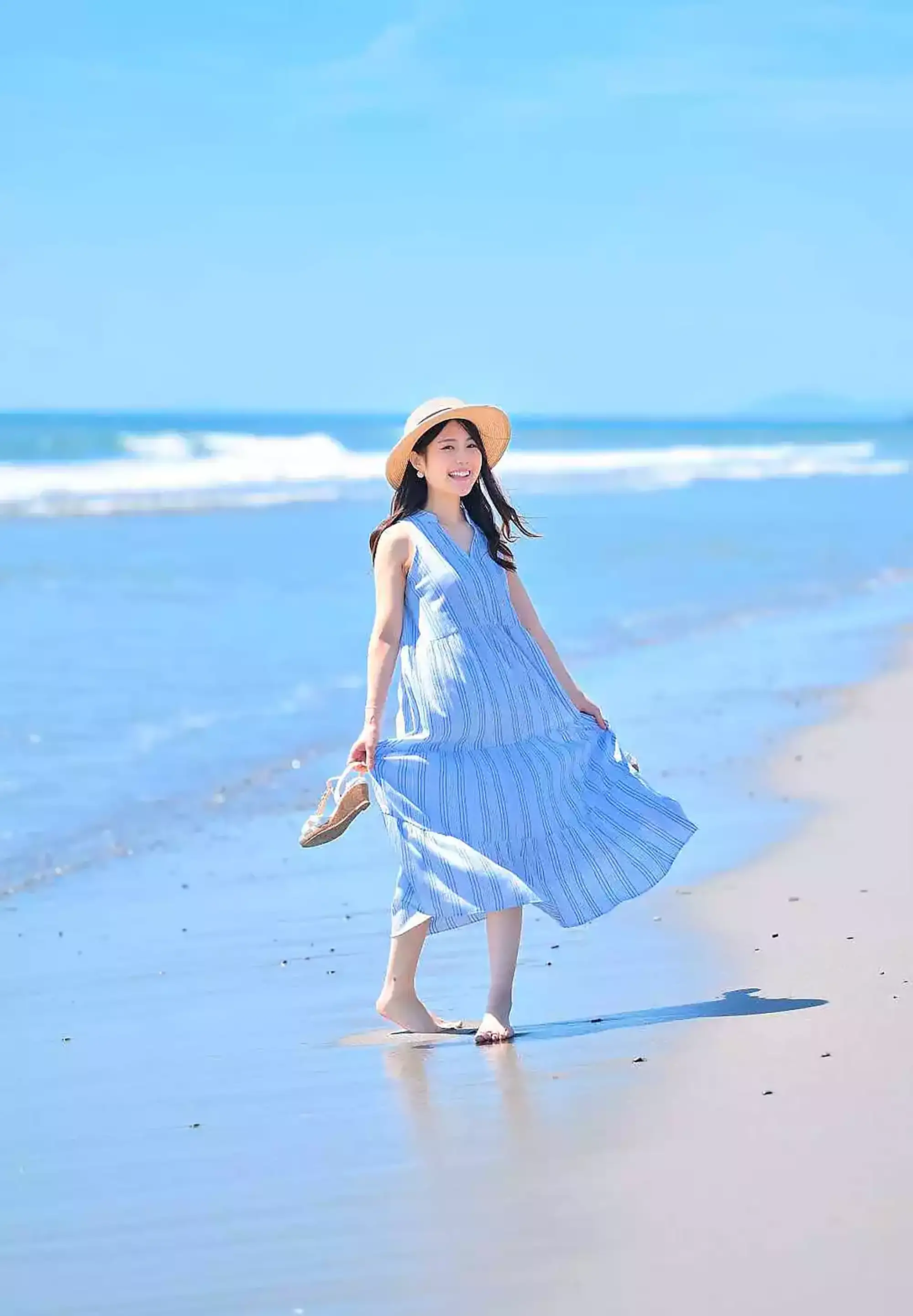 遠州灘海岸の白い砂浜と青い海を背景に、夏服の女性を撮影したロケーションポートレート