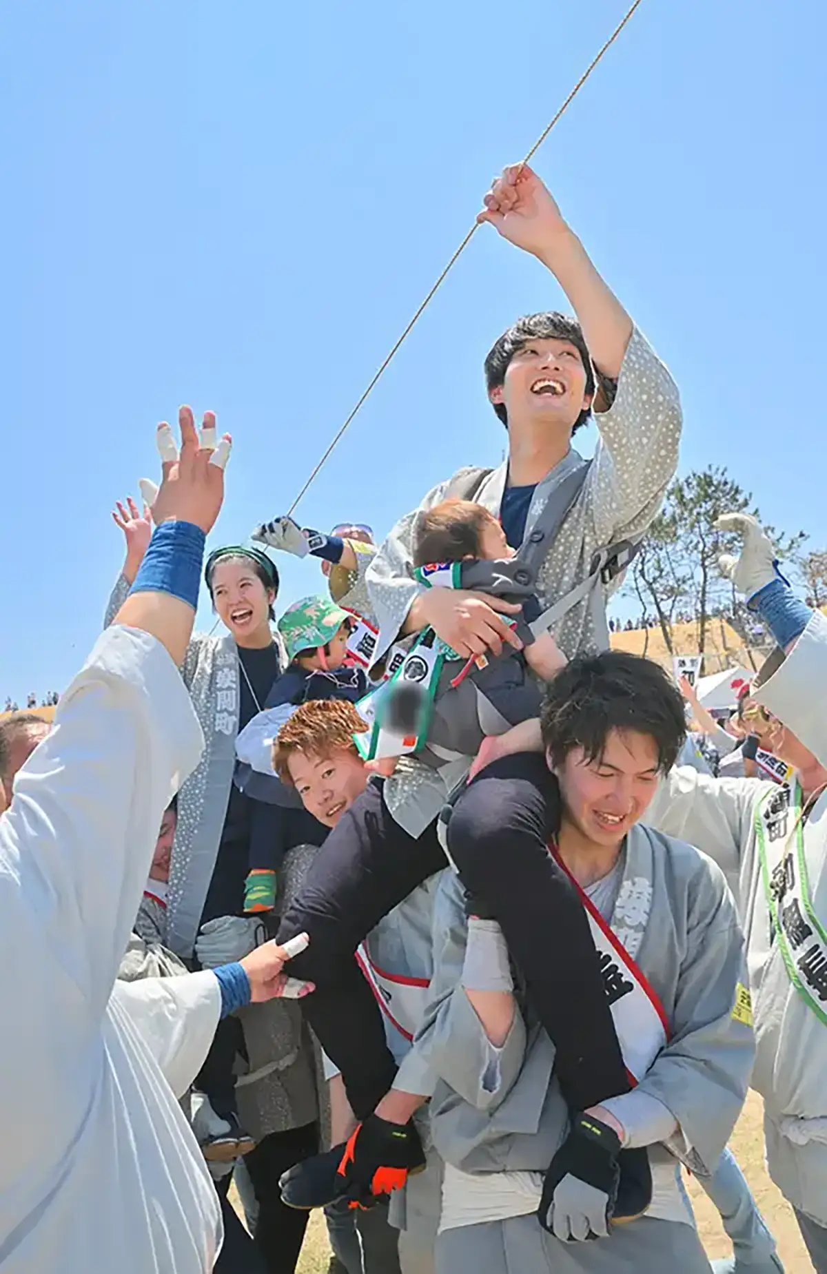 浜松まつりの初凧祝いで、家族そろって大凧の糸を手繰り寄せる成長祈願の記念写真