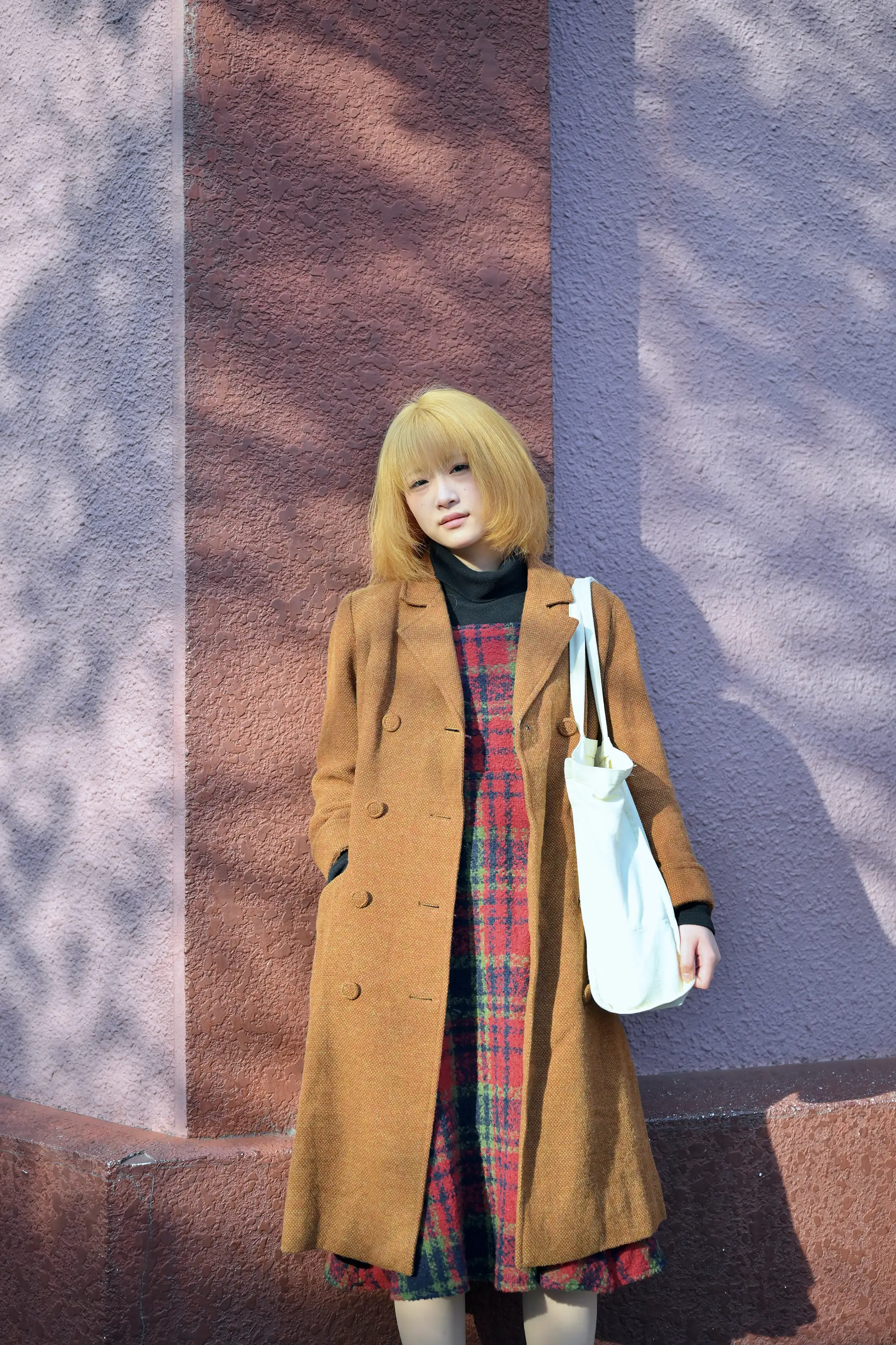 桜の木陰が落ち光と影のある外壁にもたれる女性のストリートスナップ